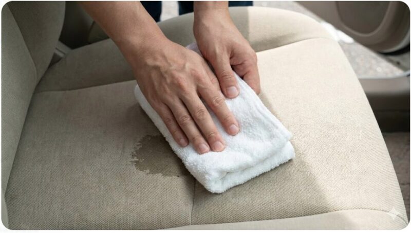 車のシートのお漏らし箇所に乾いたタオルを強く押し当てて水分を吸収させている様子