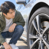走り始めのブレーキ鳴きが気になり車のホイール周辺を確認する男性