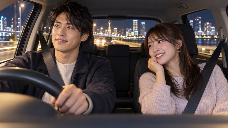 夜のドライブデートで丁寧に運転する男性と助手席から笑顔を向ける女性