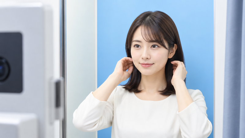 証明写真ブースで清潔感のある明るい服装と整った髪型で撮影準備をする女性